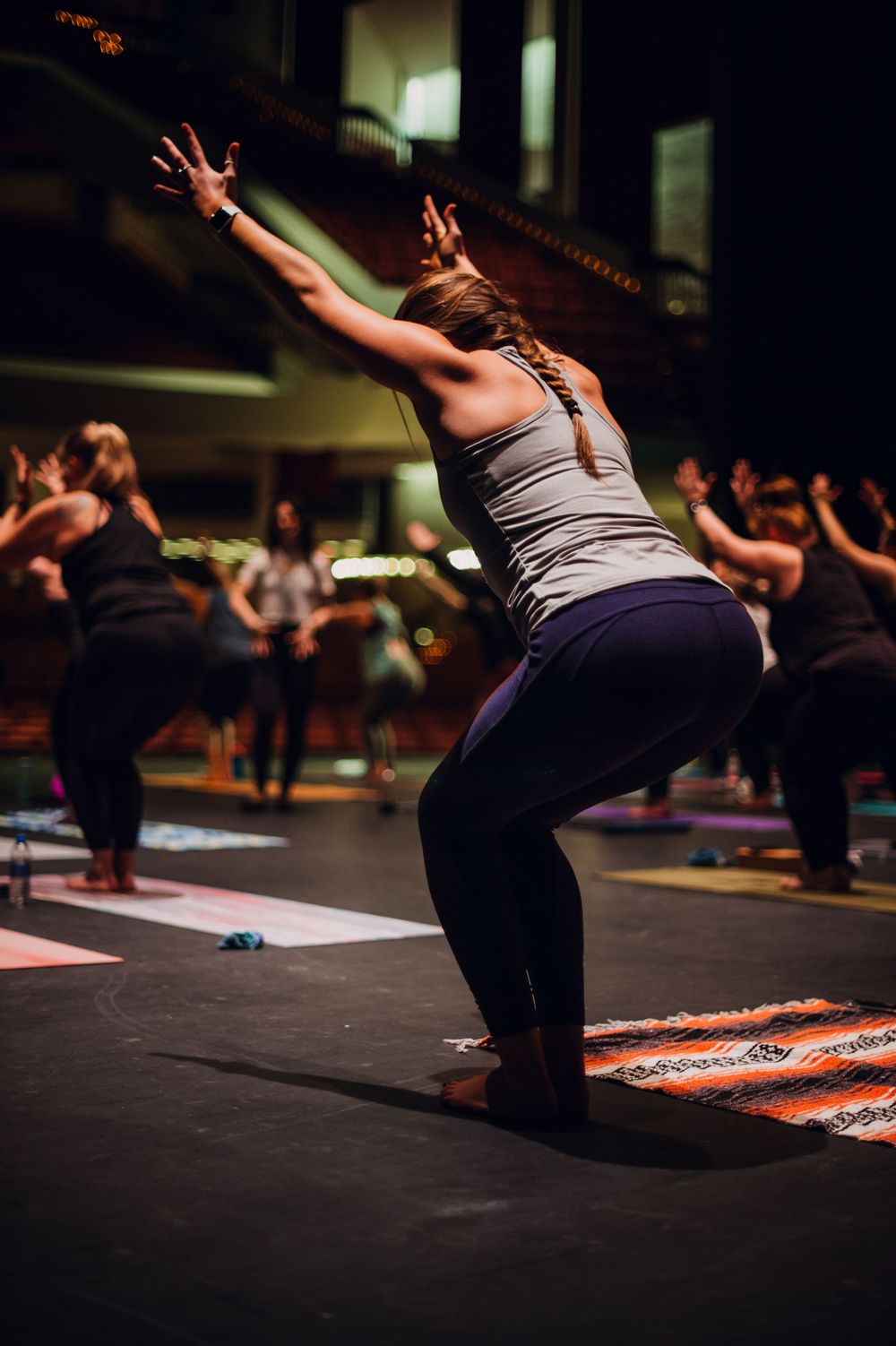 Yoga student stretches arms upward during group fitness class.