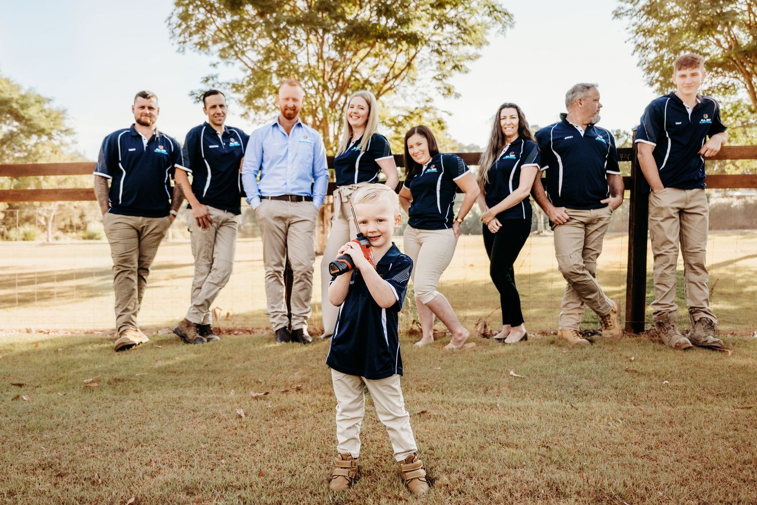Group photo of staff members in matching uniforms posing outdoors.