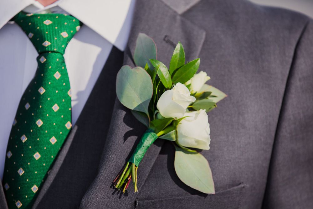 Detail shot of grey suits with emerald green ties and white boutonnieres.