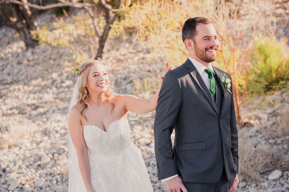 A couple shares a romantic first look moment in an outdoor desert setting with golden light.