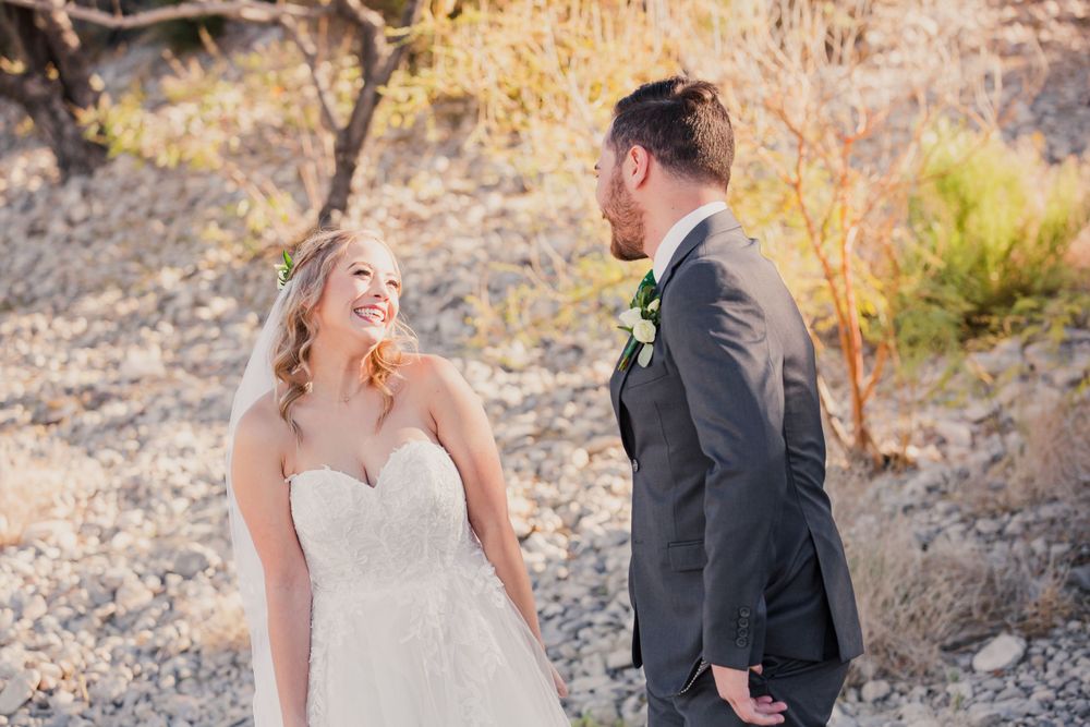 Newlyweds share a joyful moment together against a desert landscape backdrop.