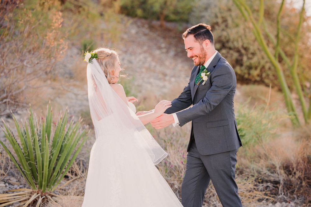 Wedding couple dancing and twirling in a desert setting with natural desert plants.