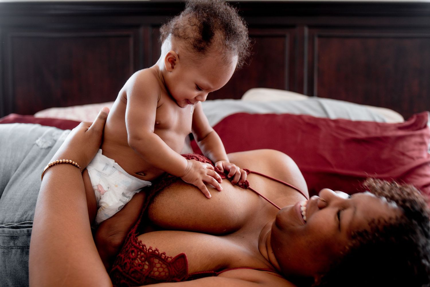A tender moment between parent and baby on a bed with red bedding.