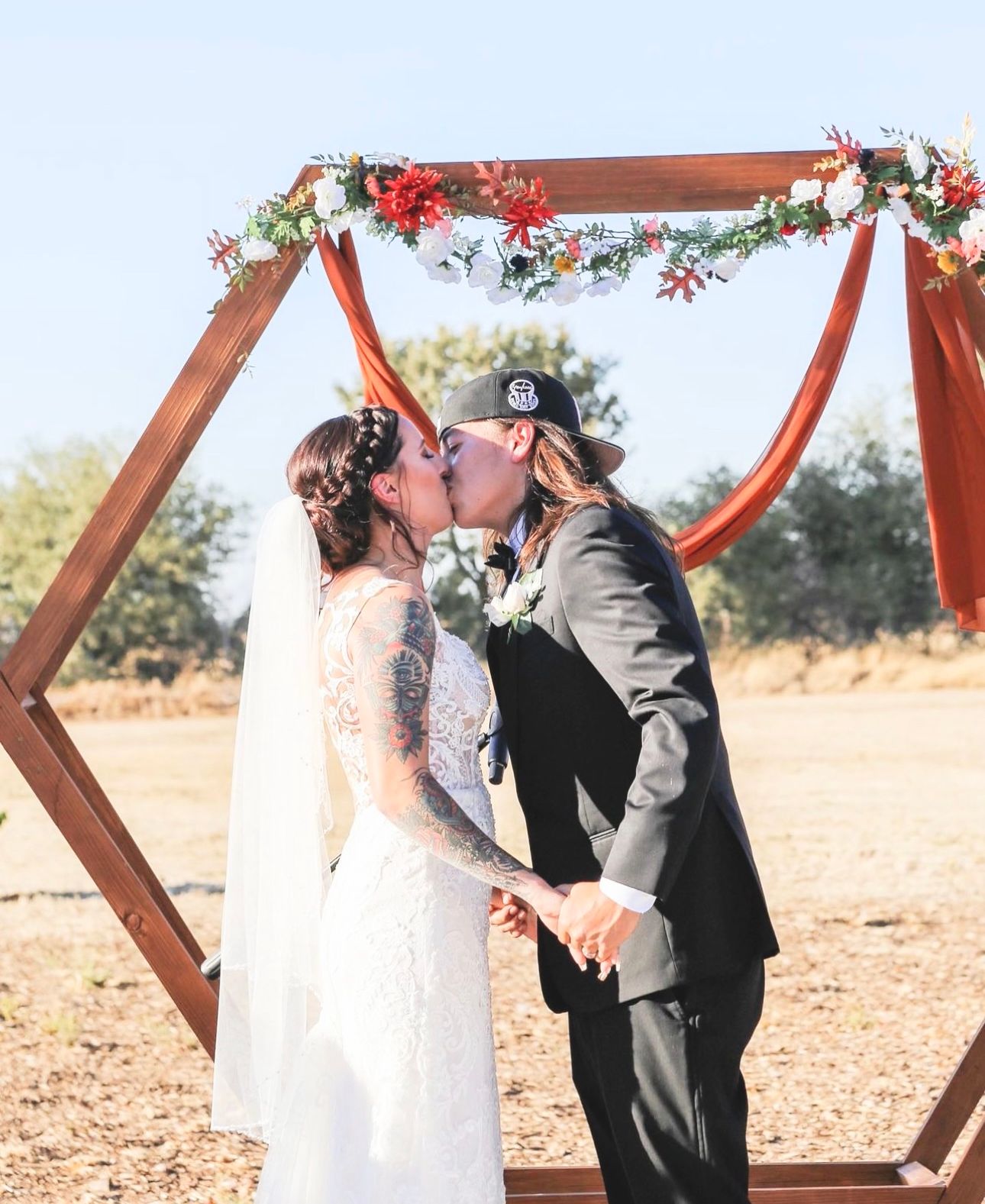 A bride and groom share a tender kiss beneath a beautiful archway during their enchanting wedding ceremony.