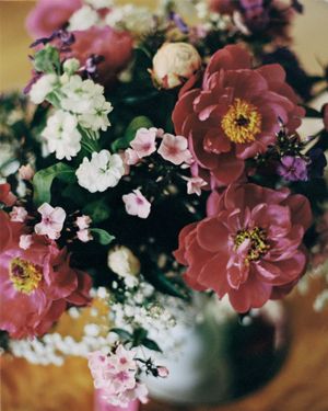 Lush floral arrangement with pink peonies and white flowers in soft focus.