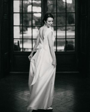 Elegant white wedding gown with open back photographed in front of large window.