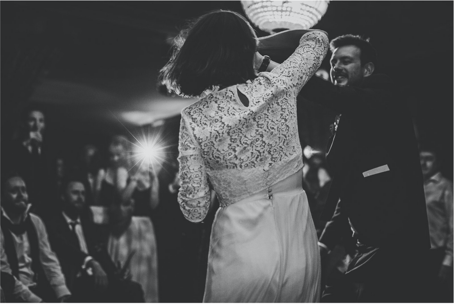 Bride and groom dancing with guests in the background