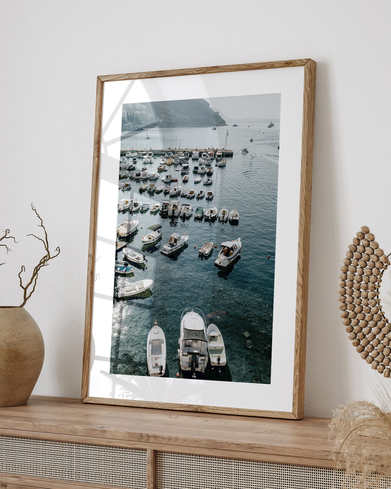 Framed black and white aerial photograph of boats moored in a Mediterranean harbor displayed on a wooden shelf.