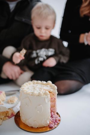 Close-up of white frosted celebration cake with family in background.