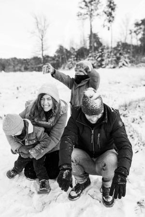 Group enjoying winter fun in the snow, playing and laughing together in black and white.