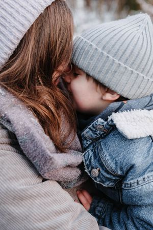 Tender winter moment between parent and child wearing knit hats and warm clothing.
