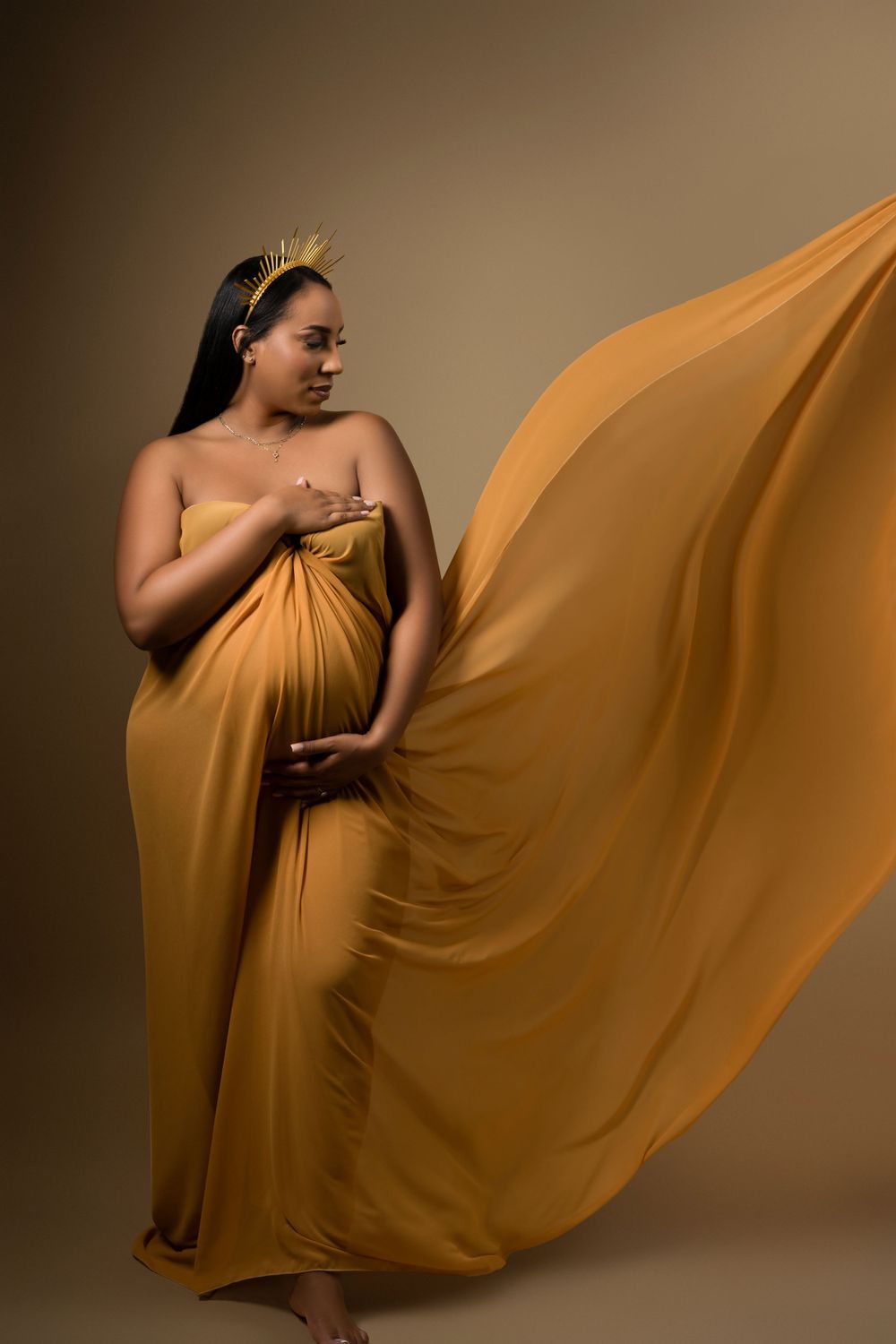 A flowing mustard yellow dress creates dramatic movement in this artistic maternity photo.