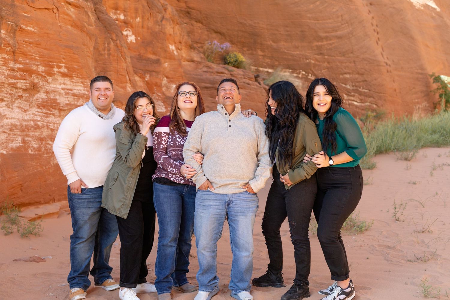 A group poses together against red rock formations in casual attire.