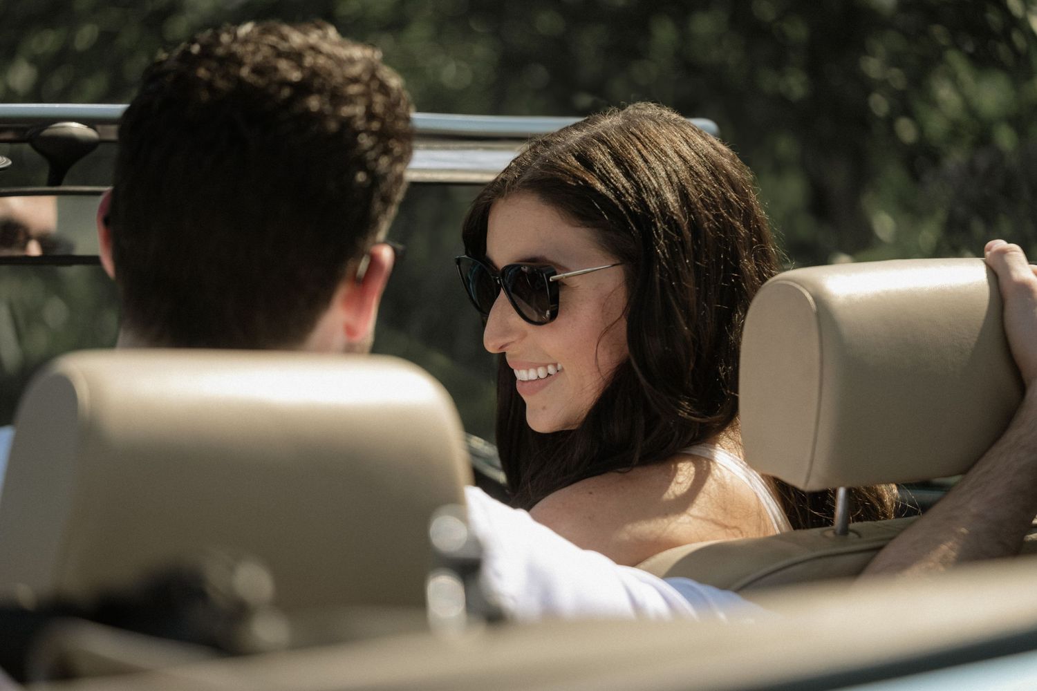Couple enjoying a drive in a convertible car on a sunny afternoon.