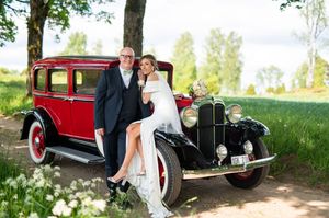 Förälskat brudpar poserar vid en fin gammal bil