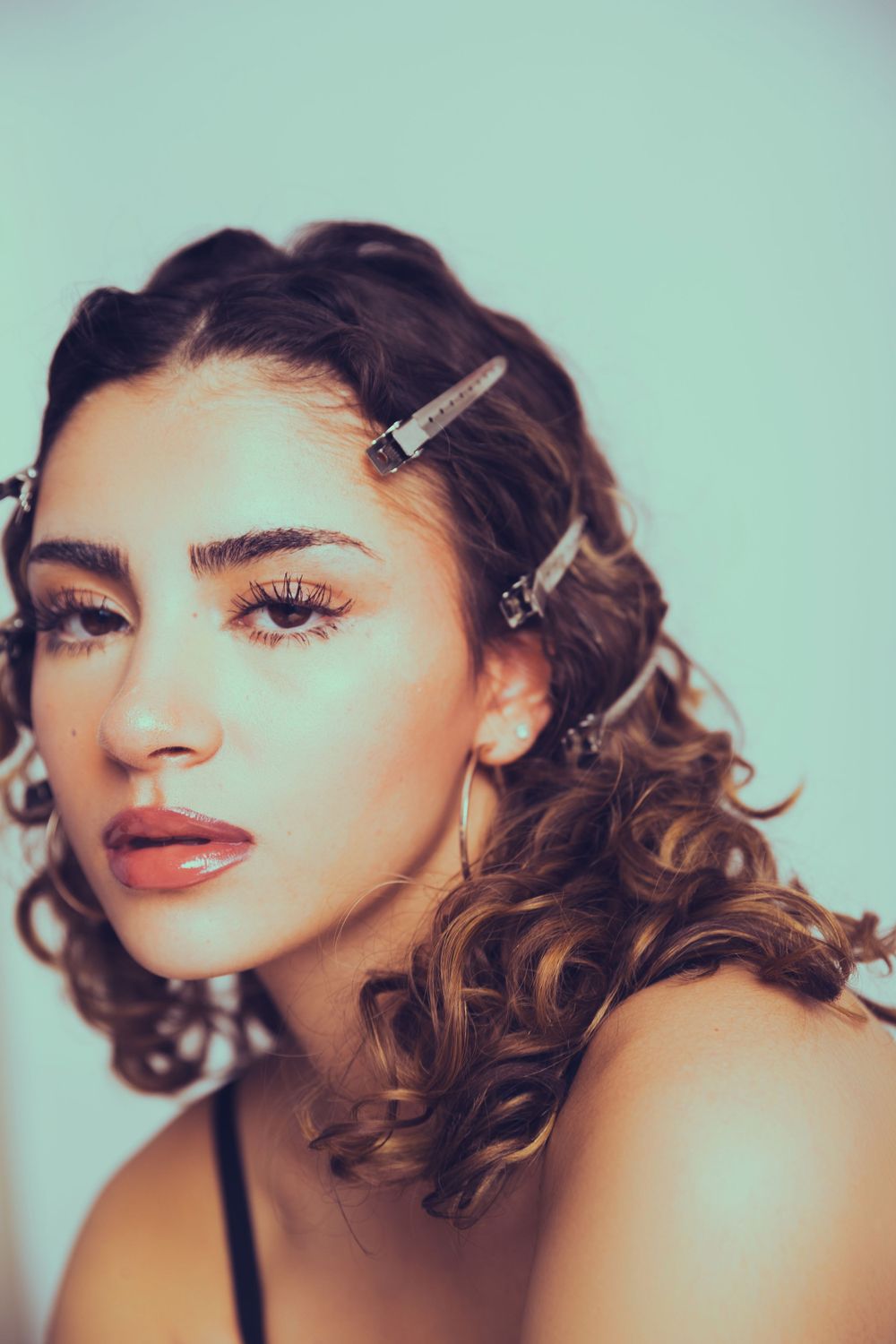Beauty portrait with vintage inspired hairstyle featuring hair clips against mint background.