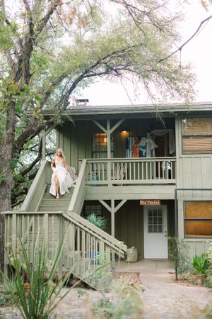 Modern rustic building with wooden staircase and green exterior surrounded by trees.