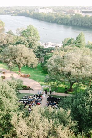 Aerial view of outdoor wedding venue with river and trees in background.
