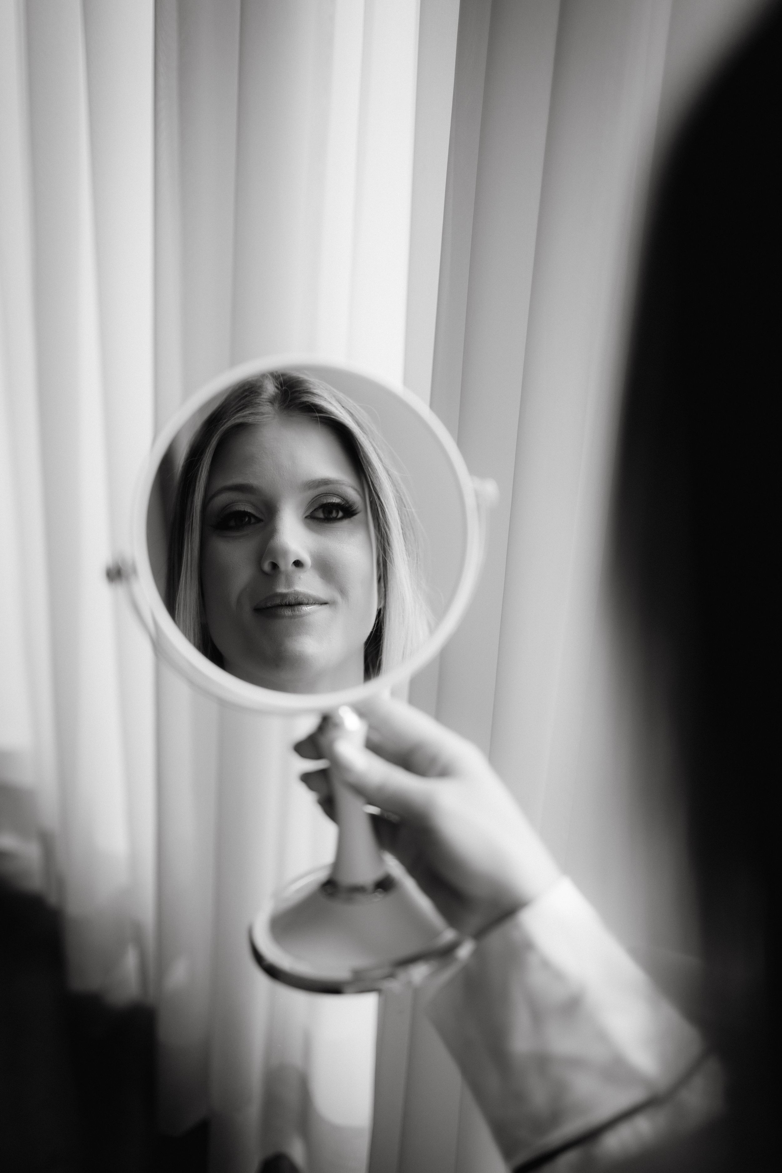 Black and white image of a reflection in a round vanity mirror.