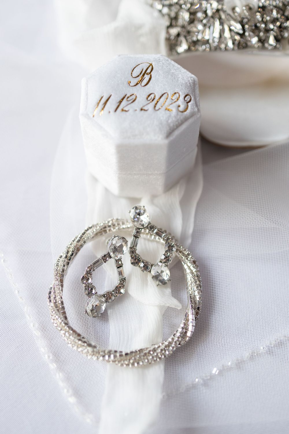 Crystal pendant and wedding ring box with gold date inscription displayed on white silk.