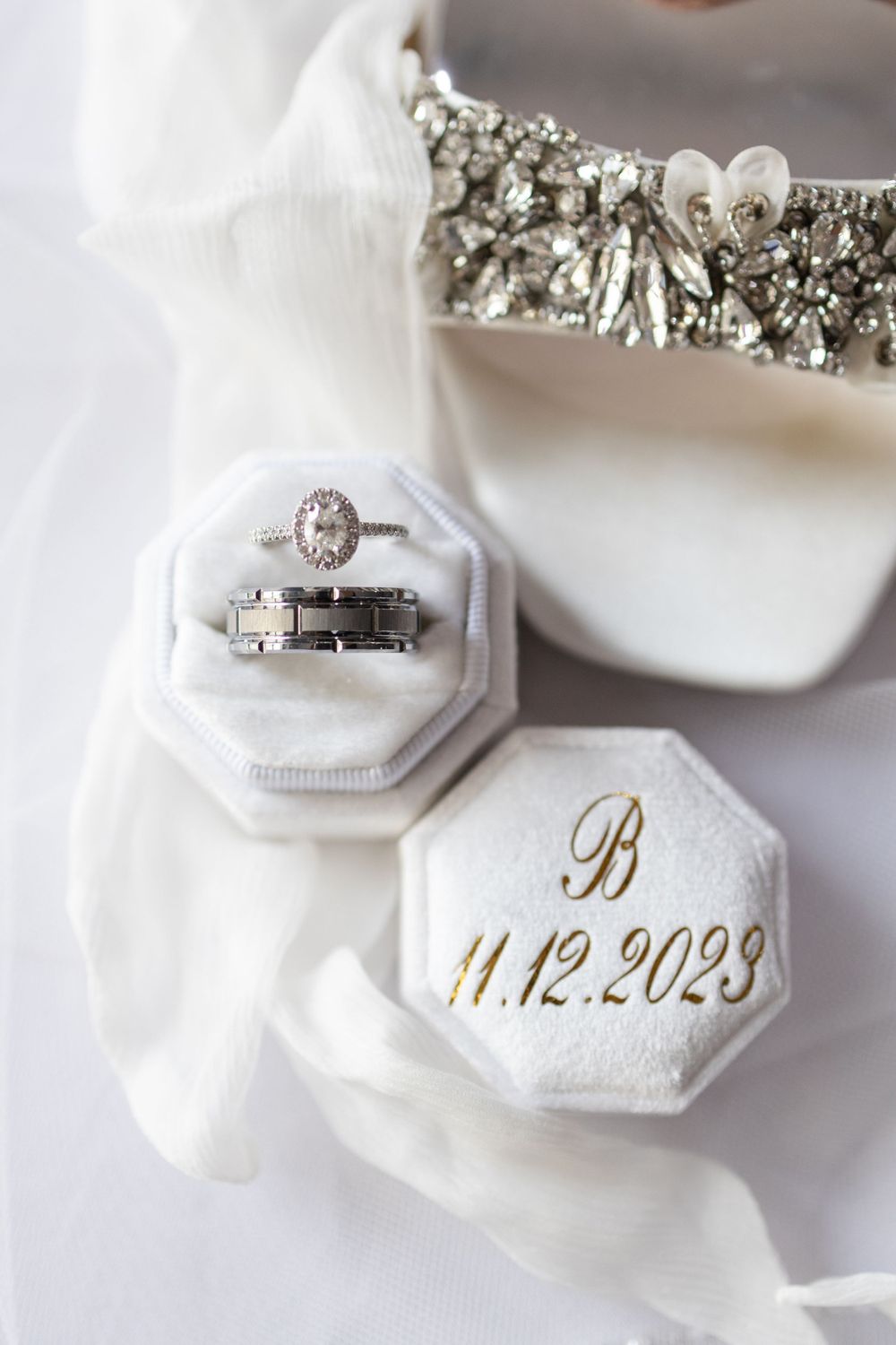 Wedding rings nestled in white octagonal boxes with gold monogram and date.