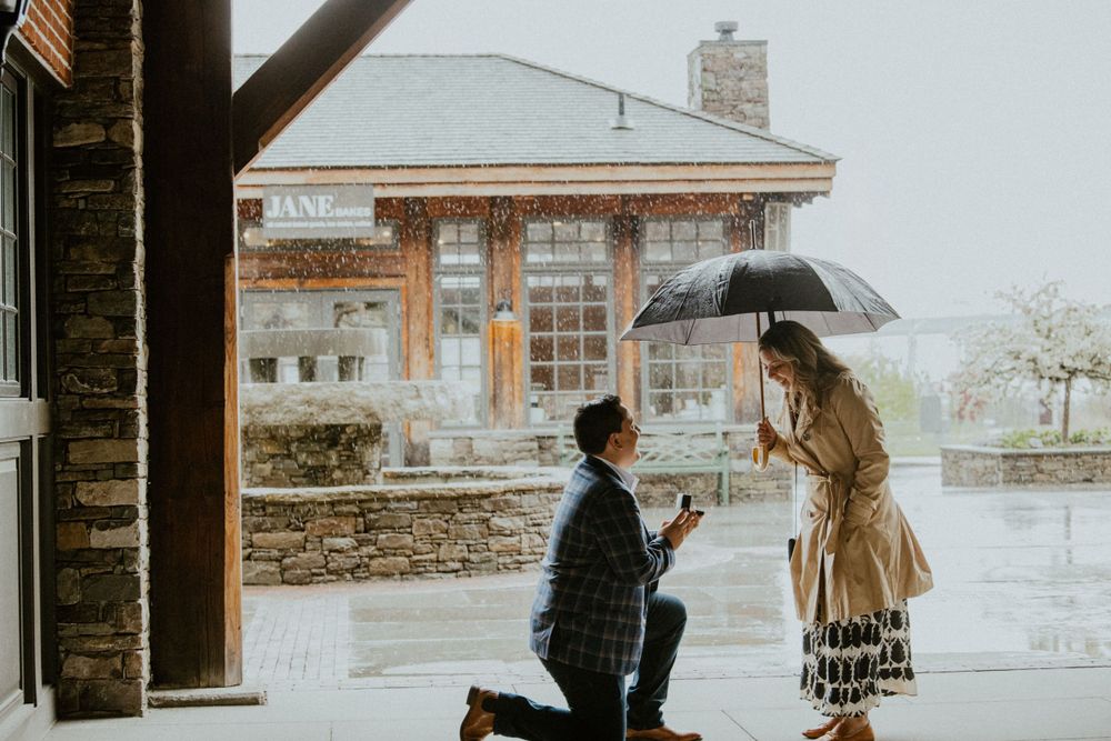 A romantic proposal scene in the rain with an umbrella on a city street.