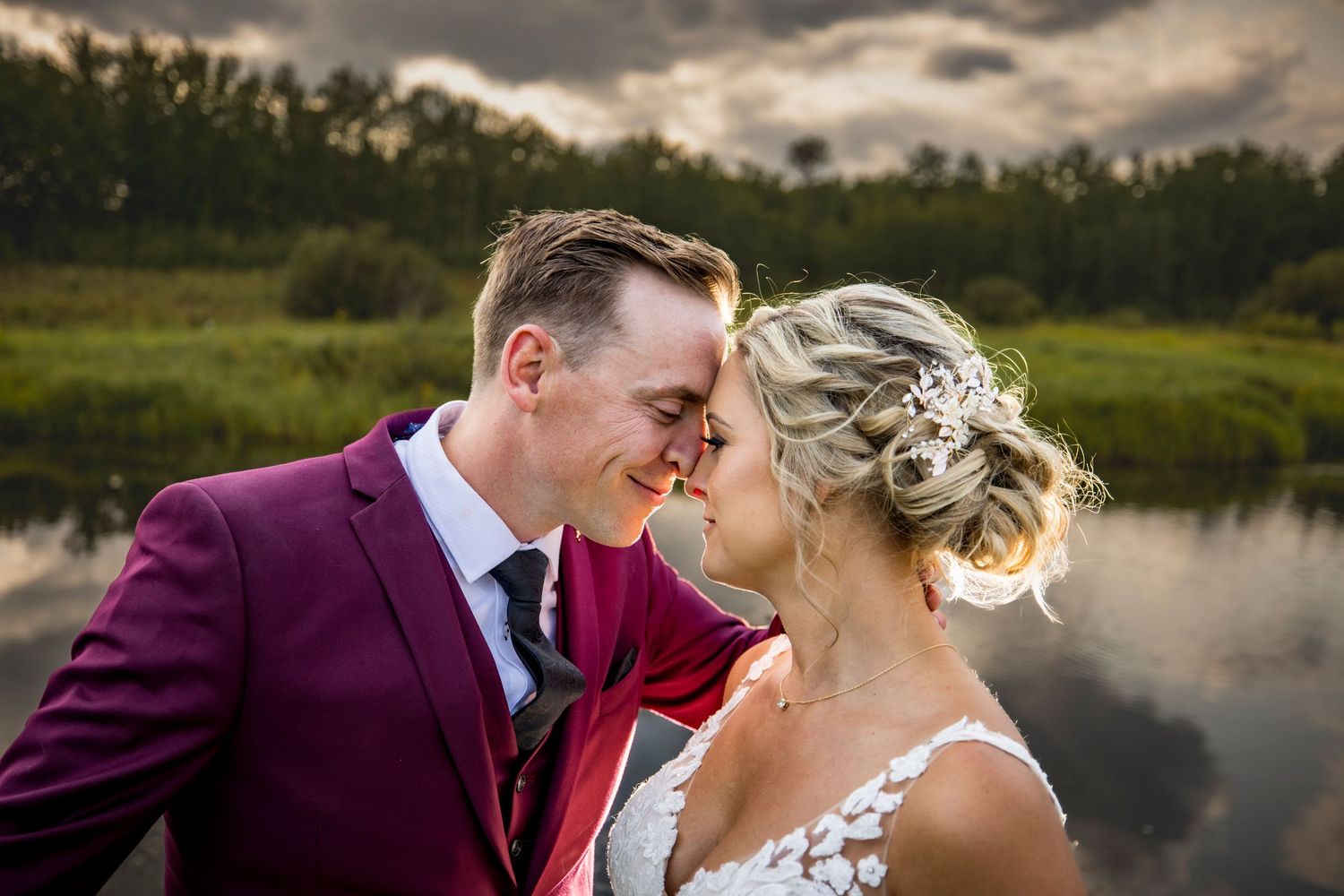 Romantic wedding portraits against a dramatic cloudy sky and lakeside landscape.