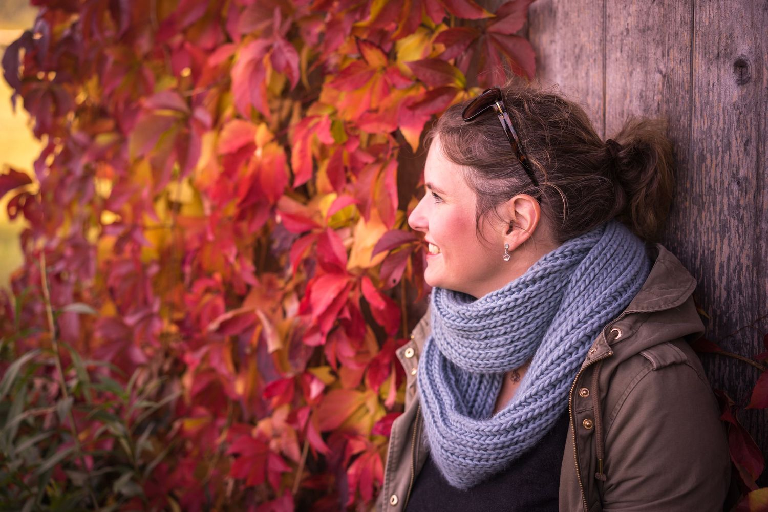 Portraitfoto einer jungen Frau an einer Scheune mit roten Herbstblättern bei einem Businessfotoshooting in Wien