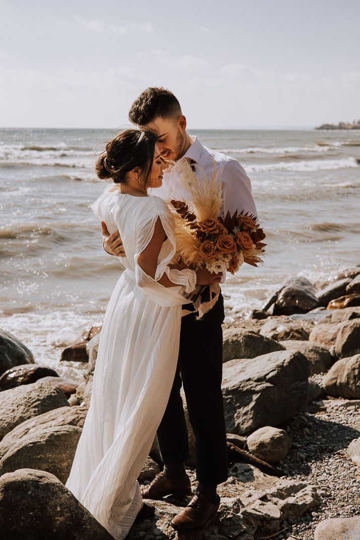 Bride and groom embracing on their wedding day photo session on the beach.