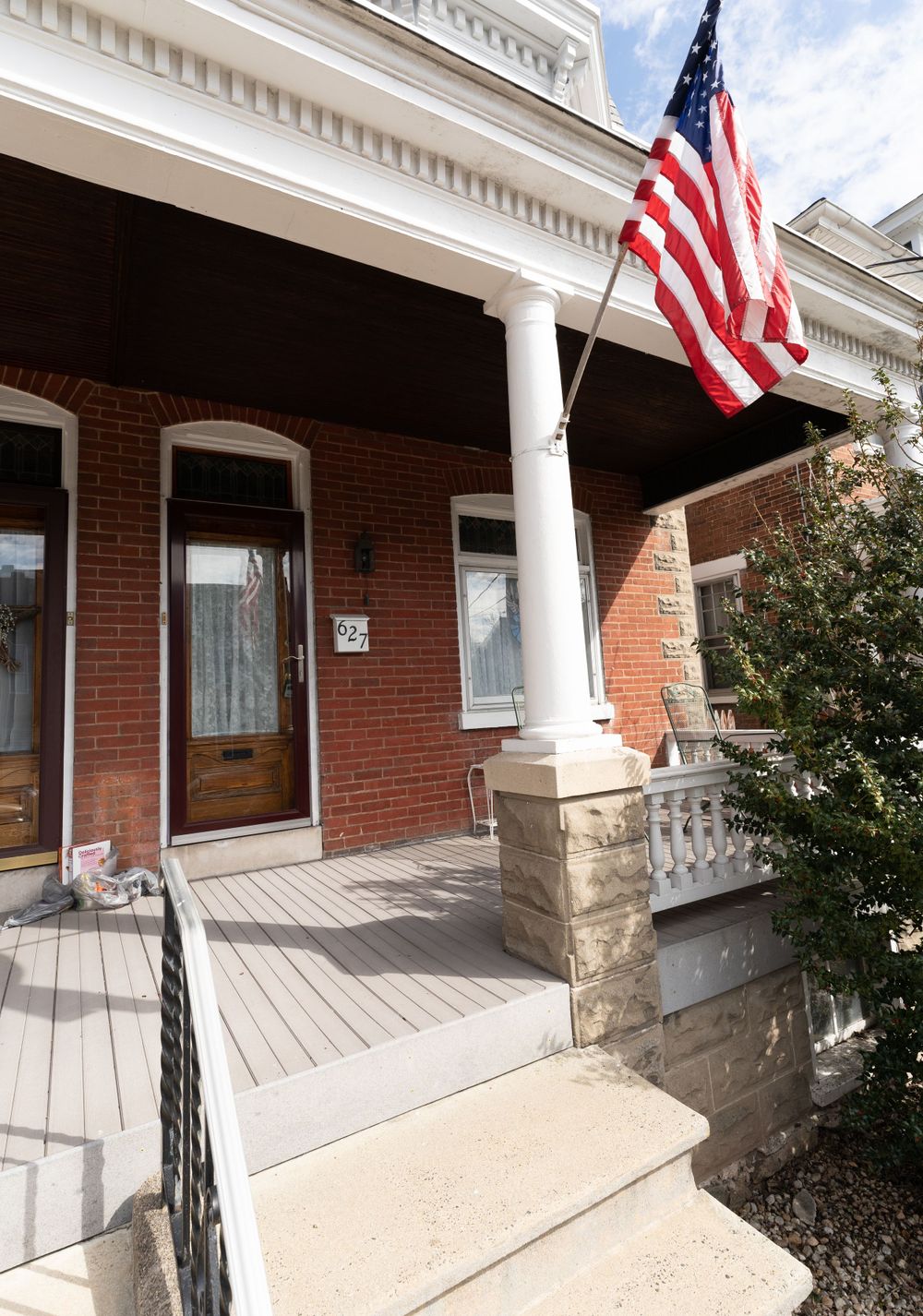 Brick house entrance with white columns and an American flag flying from the porch.