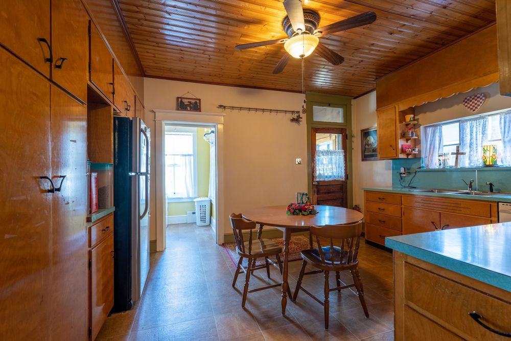Vintage kitchen with wood paneled ceiling and walls displays classic wooden furniture and appliances.