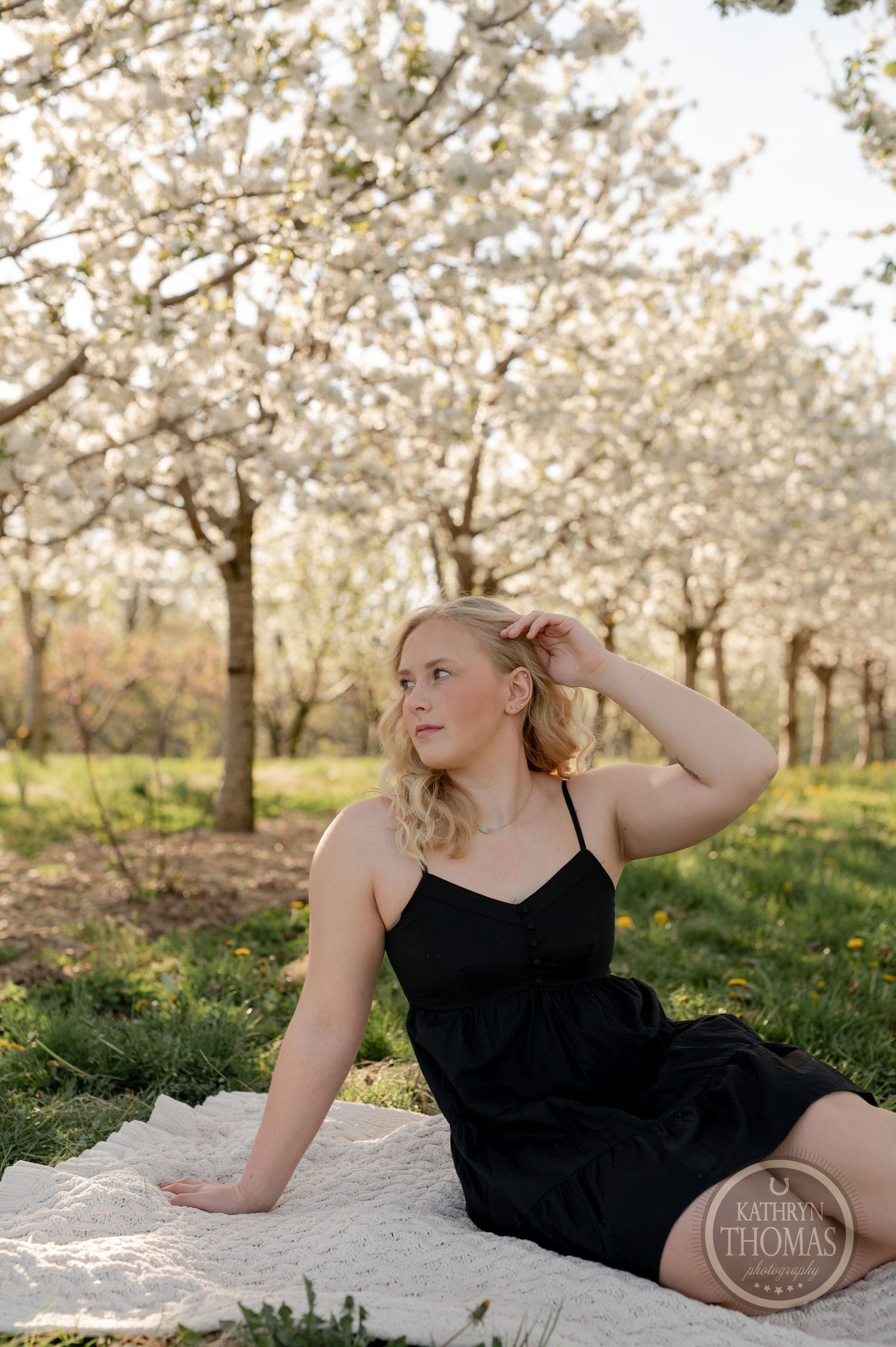 Elegant outdoor portrait session on a blanket under blooming spring trees.