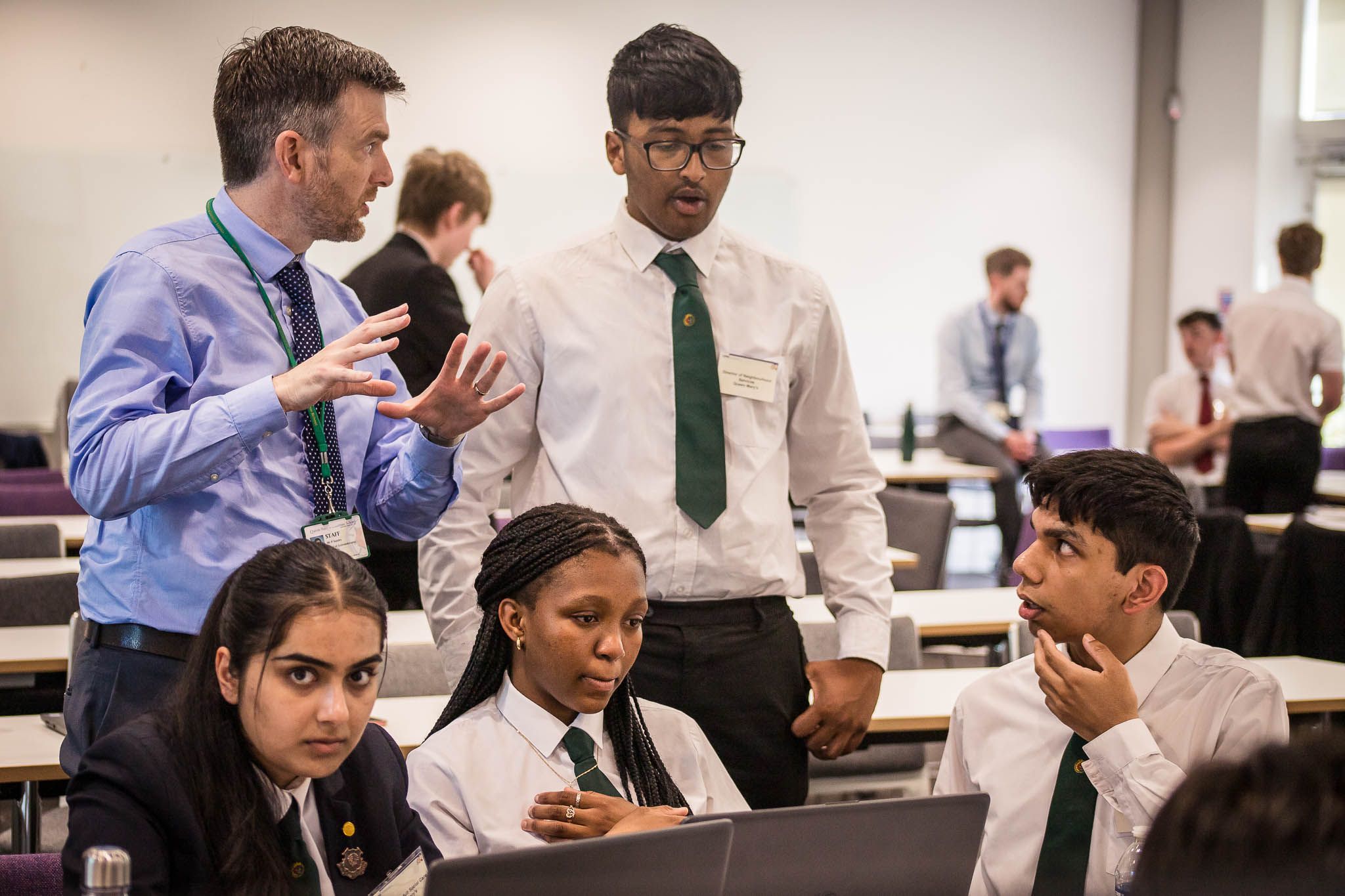 Group of students working hard with the help of a teacher at an event at Birmingham University