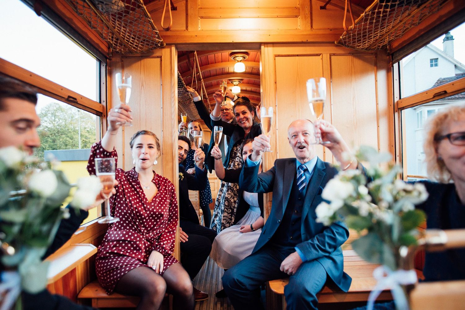Celebratory gathering inside vintage train car with floral decorations.
