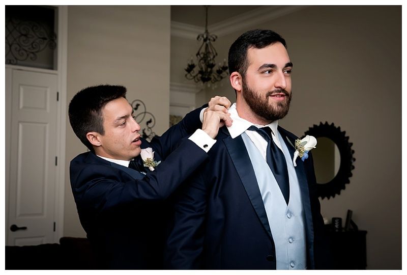 Groomsmen in dark suits preparing for wedding ceremony.