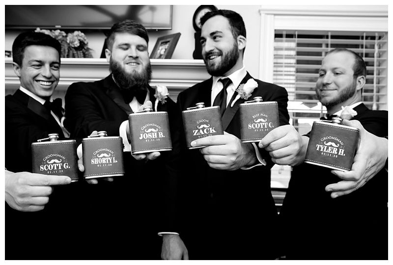 Groomsmen toasting with personalized flasks in a celebratory moment.