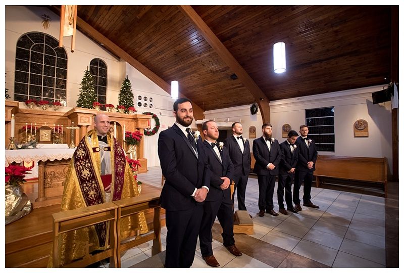 Wedding ceremony taking place in a church with wooden beams and pews filled with guests.