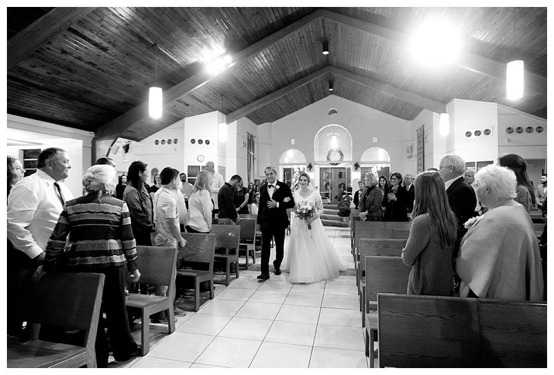 Wide angle panoramic view of a church wedding ceremony with wooden ceiling and pews.