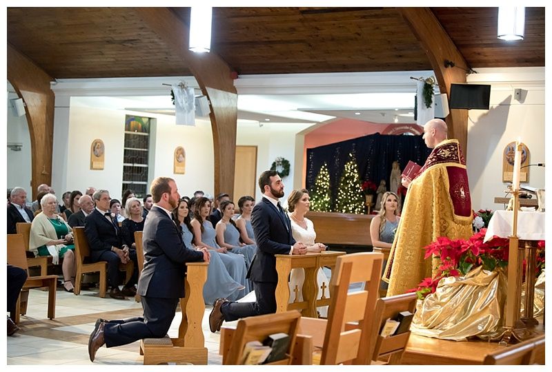 Side view of wedding ceremony showing wooden pews and guests in a church setting.