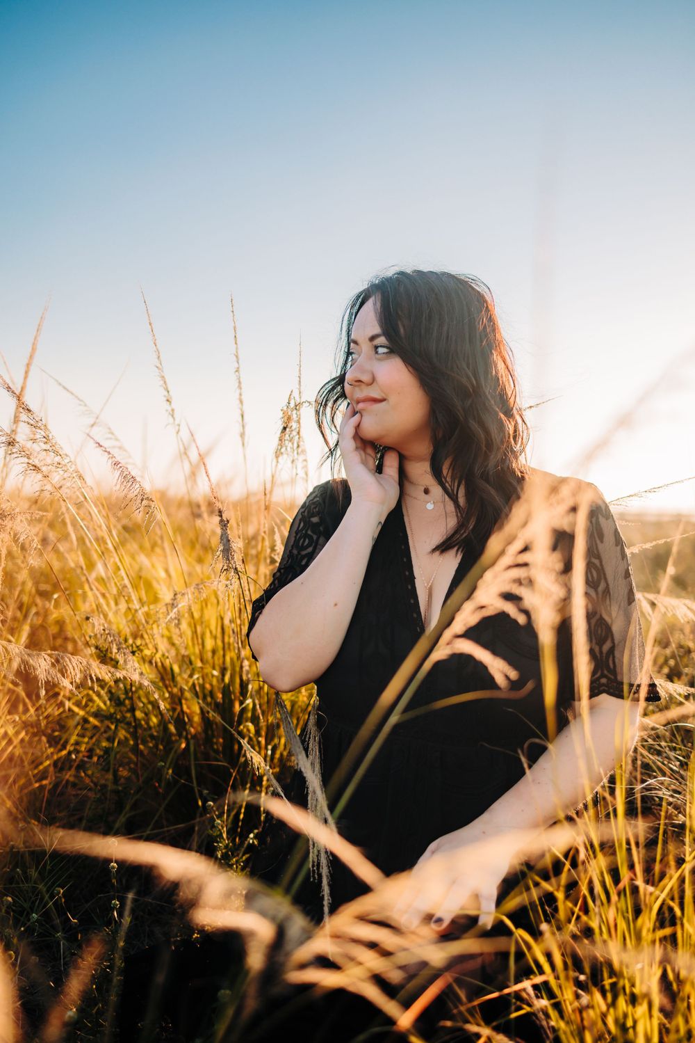 Artistic portrait in a golden wheat field at sunset with soft natural lighting.
