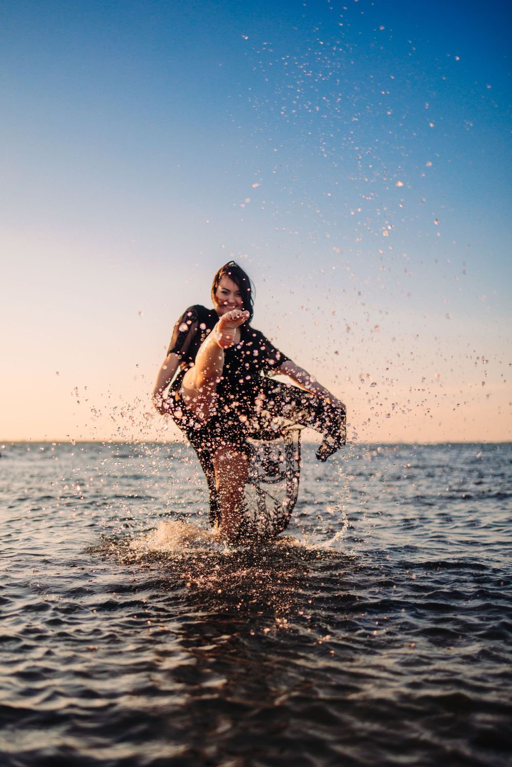 Joyful splash captured in the ocean during sunset with water droplets sparkling in the air.