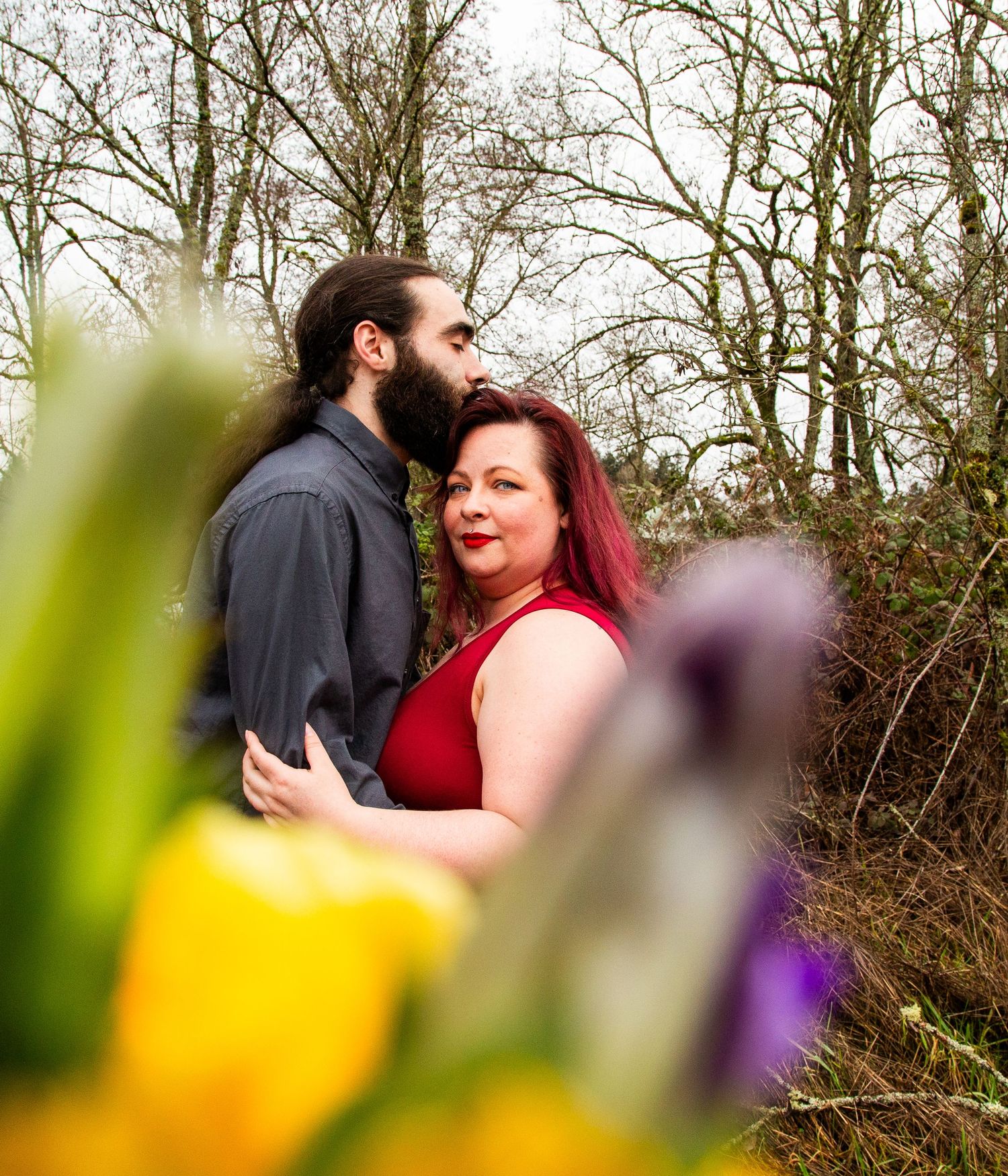 A romantic outdoor photo with bright flowers in foreground and trees in background on cloudy day.