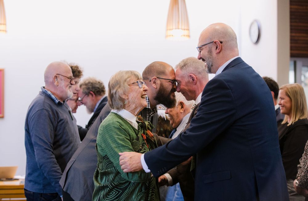 Group of people greeting and embracing at a social gathering indoors.