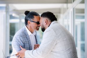 Two people sharing Maori hongi  in a bright hallway setting.