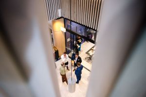 Aerial view of people gathering in modern office lobby with geometric lighting fixtures.