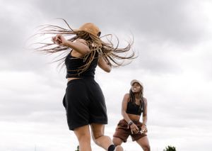 Two dancers moving expressively against a cloudy sky backdrop.
