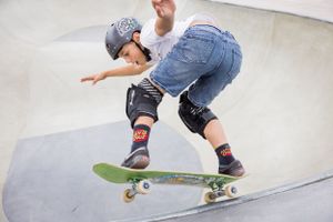 Skateboarder performing trick on ramp wearing protective gear and jeans.