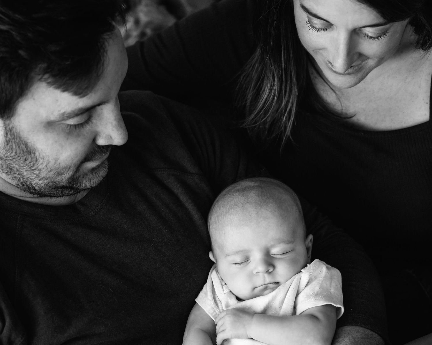 artistic black and white image of parents looking down at sleeping infant