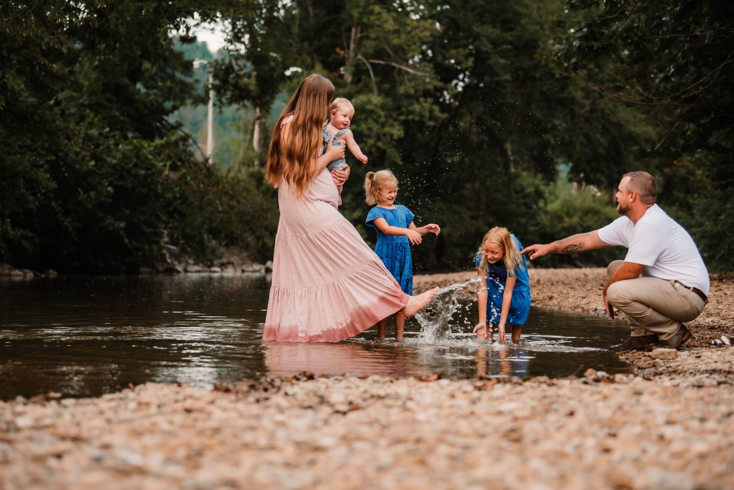Family playing together in a shallow creek on a summer afternoon.