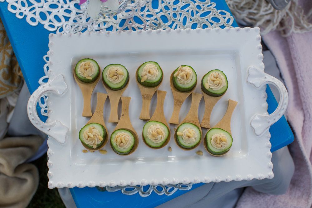 Small cucumber appetizers garnished with herbs arranged on a white decorative serving tray.